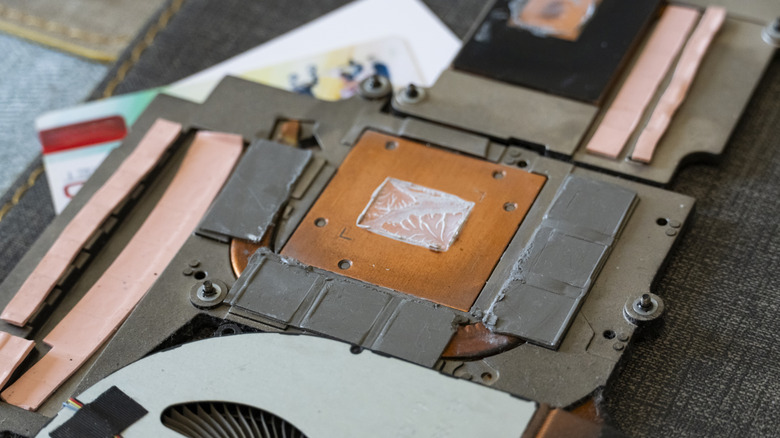 Laptop heatsink assembly with thermal pads and thermal paste exposed during maintenance.