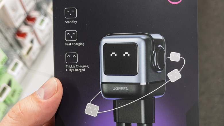 A hand holding a Ugreen charger in its box in a store