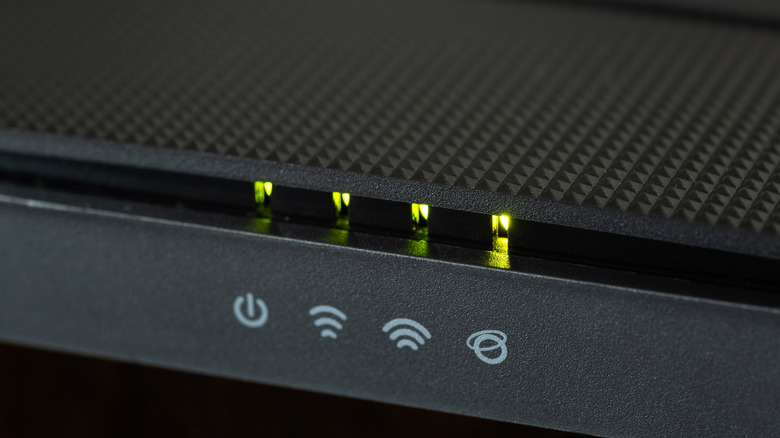 Front of a Wi-Fi router with symbols and green lights showing network status.