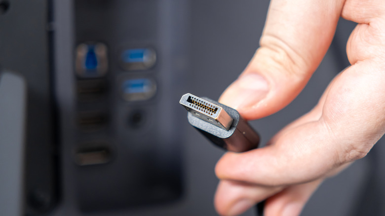 A hand holding a DisplayPort cable.