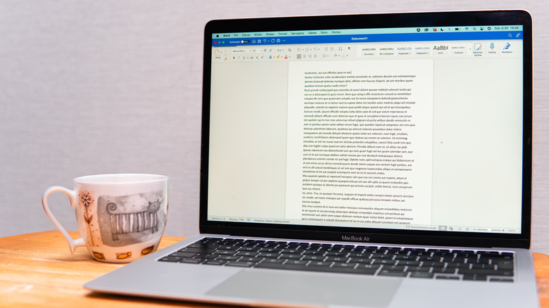 word document open on laptop next to teacup