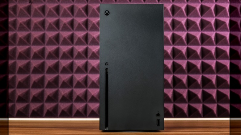 The Xbox Series X displayed against a red cushioned backdrop.