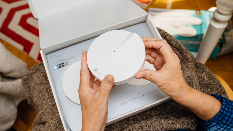 A person unboxing a Wi-Fi mesh system