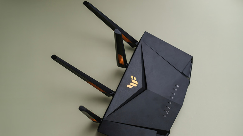 asus tuf gaming ax4200 router in a powered-off state placed against a green surface