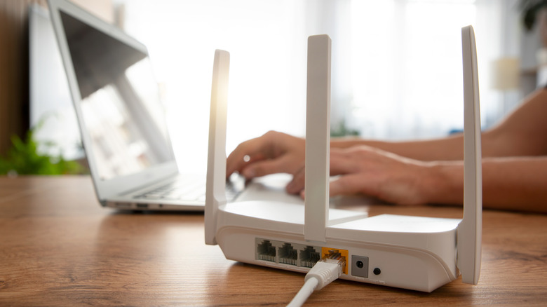A laptop user sets up near a Wi-Fi router.