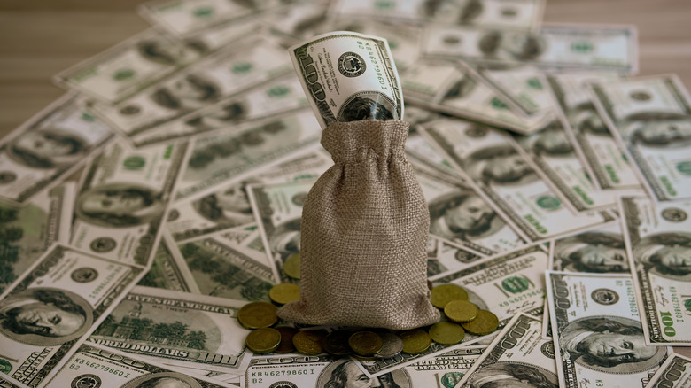 a pile of money with a bag of coins on top of it
