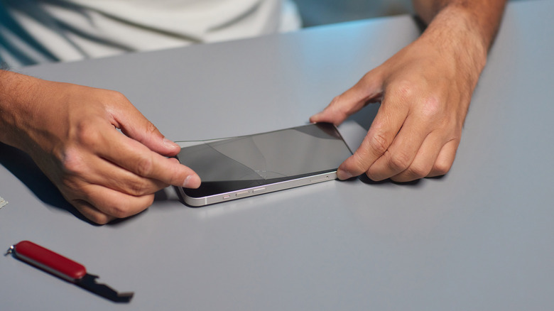 Closeup of someone applying a screen protector to a smartphone