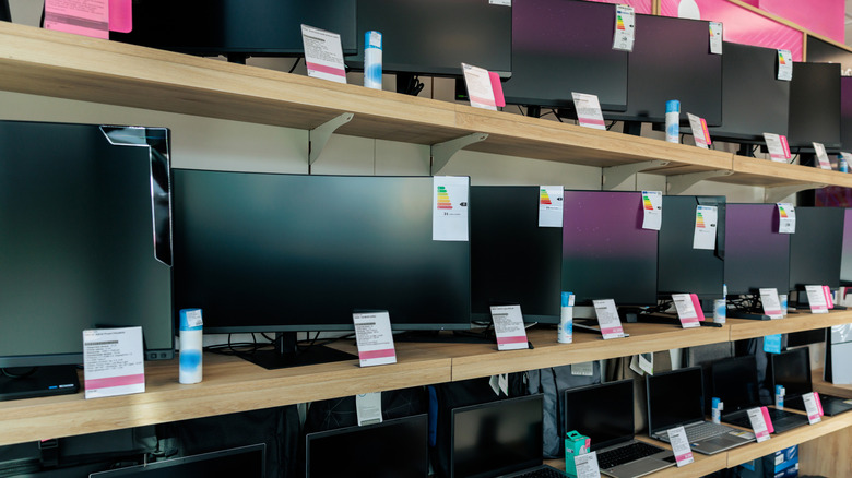 Electronics store shelves stocked with rows of computer monitors