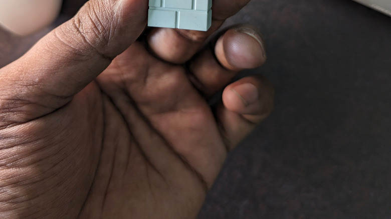 A hand holding the 8BitDo Wireless Adapter 2 for Nintendo Switch 2