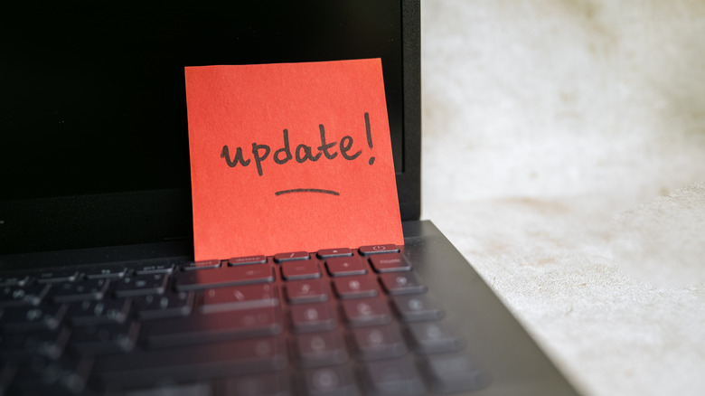 The word "update!" written on a sticky note rests on top of a laptop keyboard.