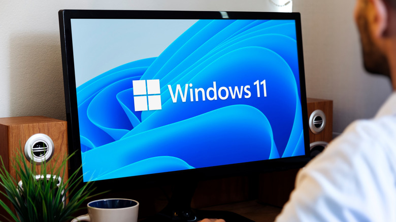 Windows 11 logo on a desktop monitor with blue background.