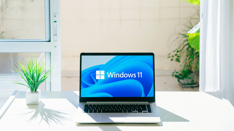 A laptop sitting on a table with the Windows 11 logo displayed on the screen.