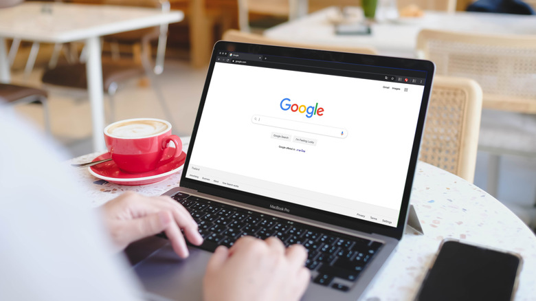 A person opening Google on their laptop in a cafe