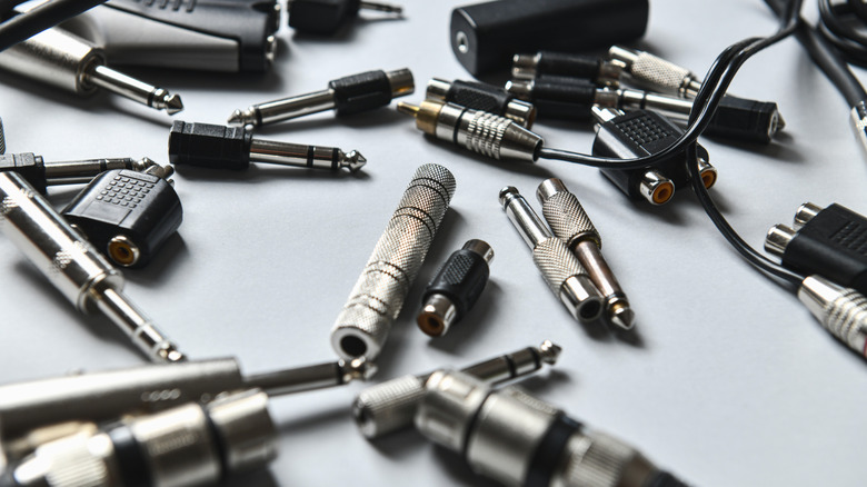 A bewildering array of audio connectors are strewn on a table.