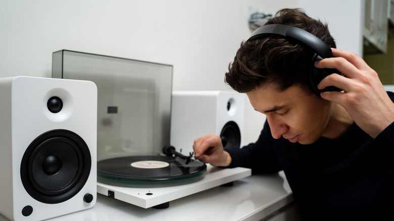 A man listens deeply while wearing headphones and operating a turntable.