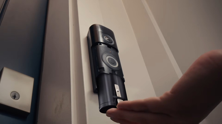 Hand installing battery on Ring wireless video doorbell mounted near door