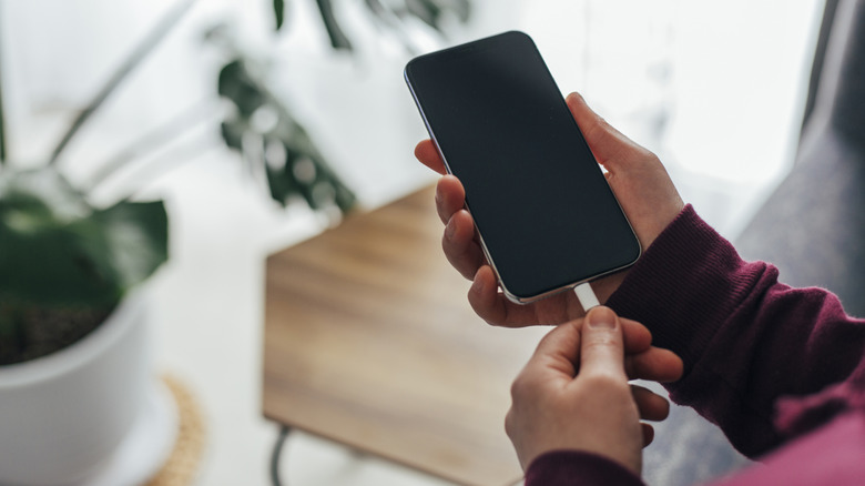 A person plugging a cable into a phone.