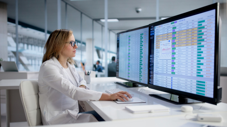 Woman working at desk with two computer monitors
