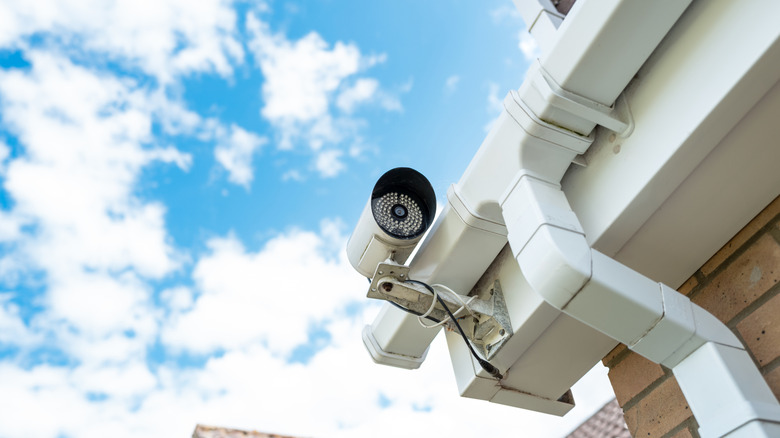 A home security camera with wires monitoring a property