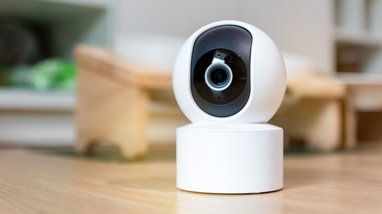 A wireless home security camera on a woodgrain surface