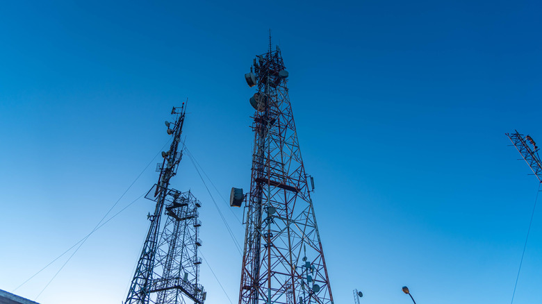 Two cell site towers against a backdrop of blue sky