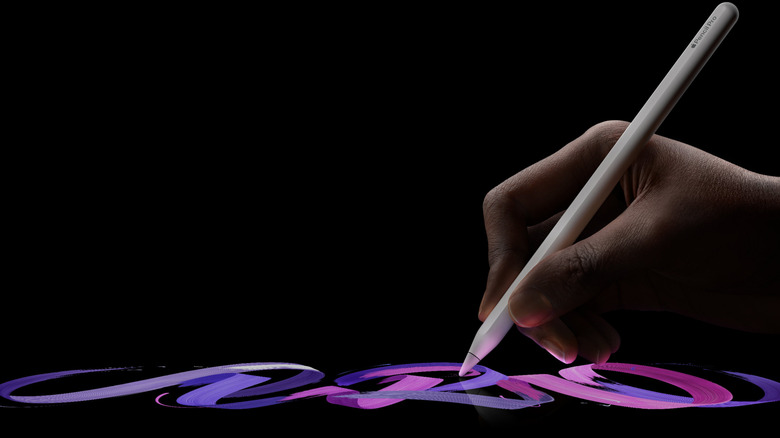 A hand holding a white Apple Pencil Pro and drawing in purple on a black background