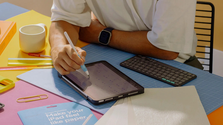 An iPad on a desk with someone writing on it