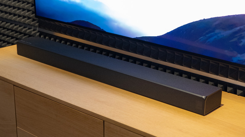 A soundbar placed below a wall-mounted TV.