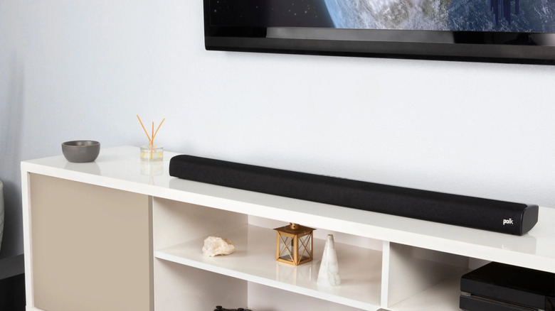The Polk Audio SIGNA S2 placed on a TV stand below a wall-mounted TV.