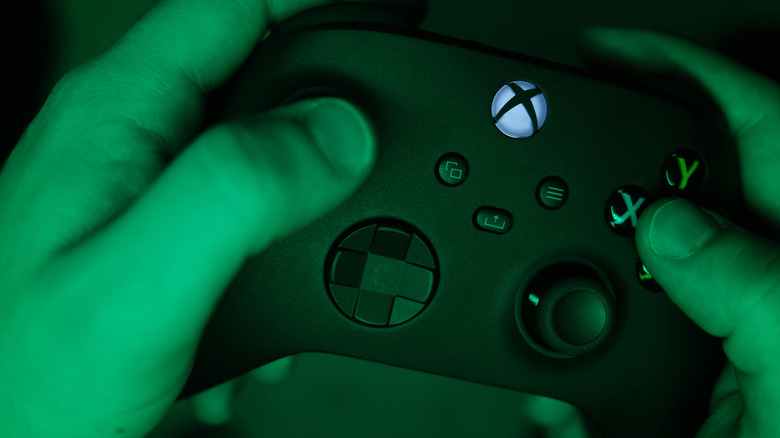 Person holding an Xbox controller with their fingers on the buttons