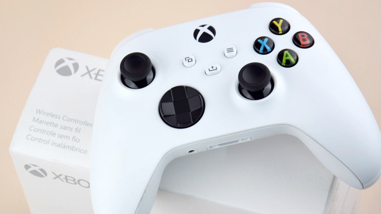 A white wireless Xbox controller sits on top of its packaging against a beige background