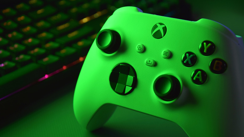 Xbox controller next to a PC's keyboard with both bathed in green light.