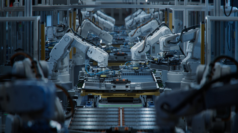 Row of robotic arms at an automated assembly line