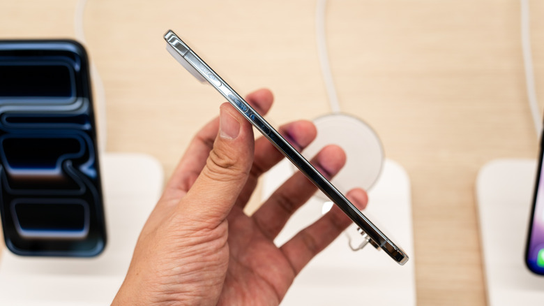 A hand holding an iPhone 17 Air sideways inside an Apple Store to detail the thinness of the device