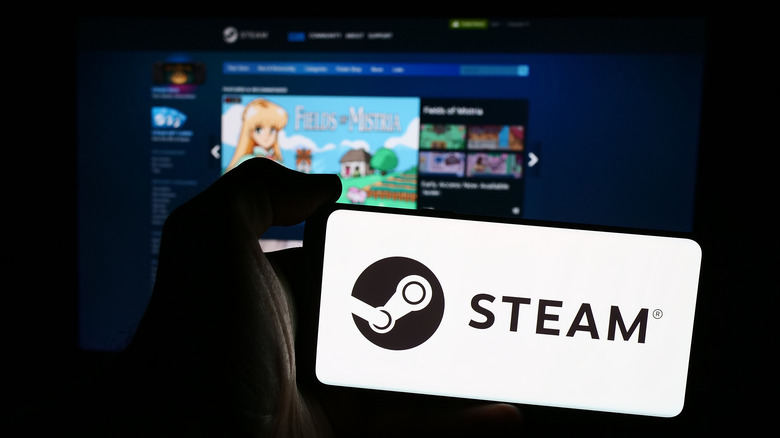 A phone showing the Steam logo in front of Steam on a larger screen