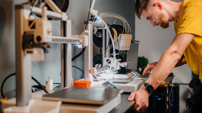 Designer working with a 3D printer in a workshop.
