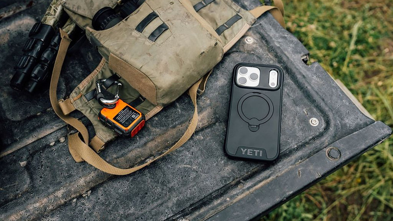 A black Yeti LoadOut phone case atop a bin with outdoor gear beside it.