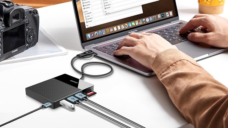 A person using a MacBook with the Yotuo Multi-Functional External Hard Drive connected to it