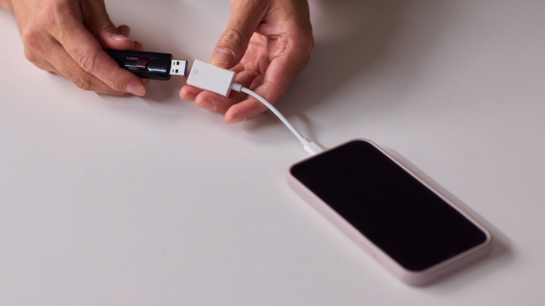 Someone connecting a flash drive to a smartphone with an OTG adapter