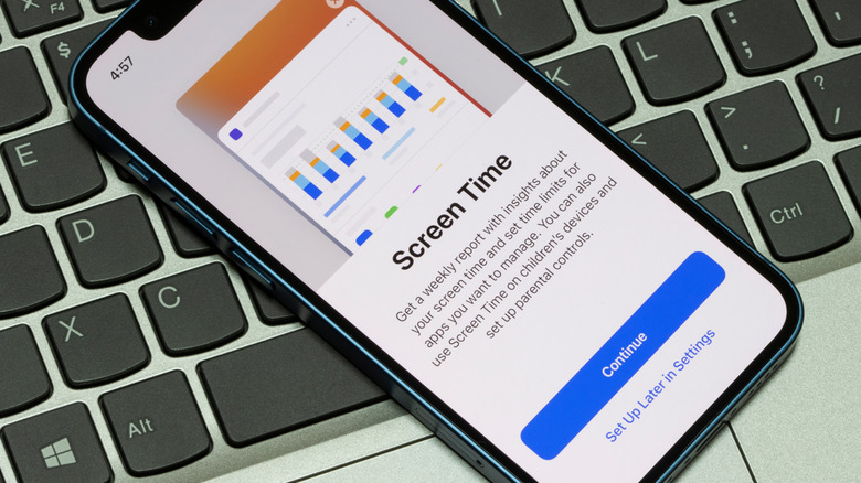 An iPhone laying on top of a laptop keyboard, the iPhone is displaying the Screen Time setup screen