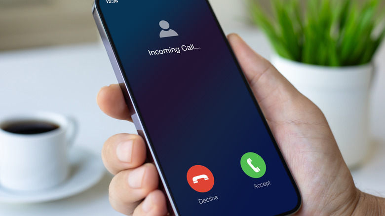 Close up of someone holding their phone with an incoming call on the screen.