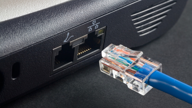 Blue Ethernet cable about to be plugged into socket.