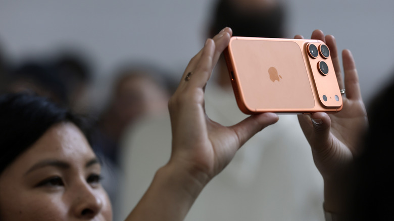A person using an iPhone 17 Pro in Cosmic Orange