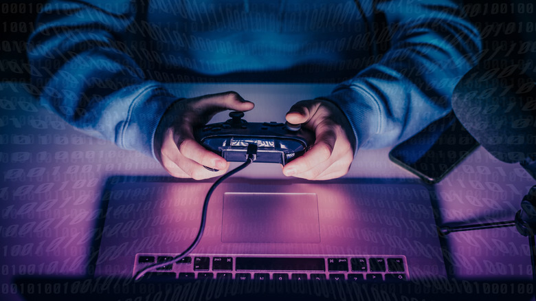top-view of a person gaming on a laptop while holding a controller