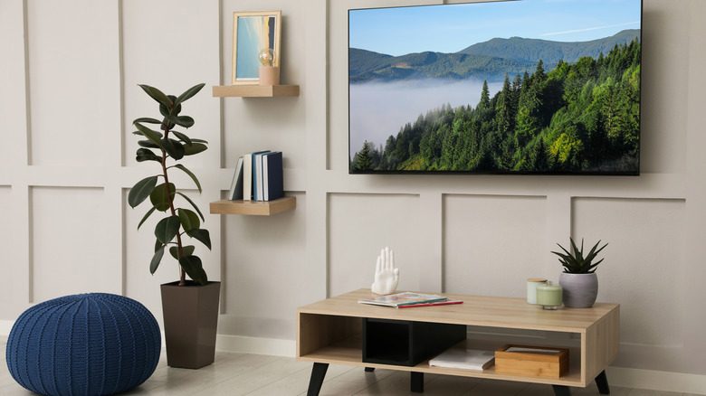 a TV mounted to a wall and a coffee table with pretty decor around it