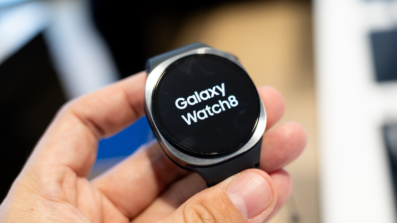 A Samsung Galaxy Watch 8 displays its logo on a Watch 8 screen being held in an individual's left hand
