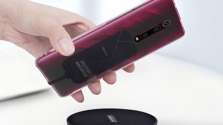 Person wirelessly charging smartphone with Nillkin Magic Tag external wireless receiver