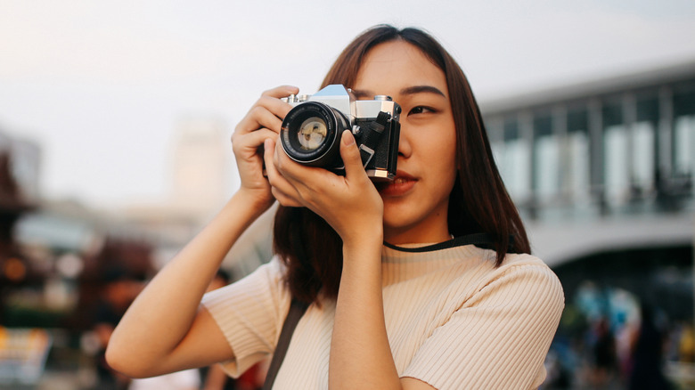 A woman using an old SLR film camera.