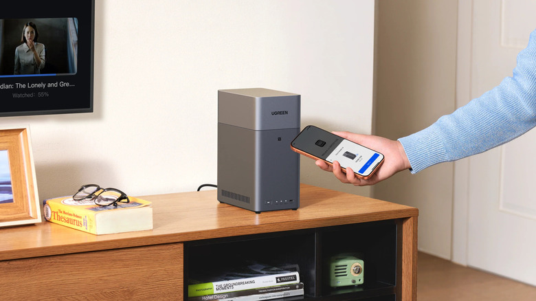 a person connects their phone to a UGreen storage device on a table