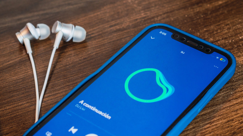 spotify DJ running on a smartphone with earbuds next to it